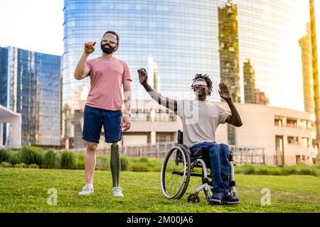 two friends who have a different disability using modern technology headsets, trying virtual reality outdoors, modern skyscrapers as background Stock Photo