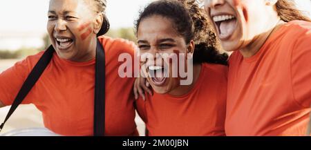 Female football fans exulting while watching soccer game at stadium - Sport entertainment concept Stock Photo