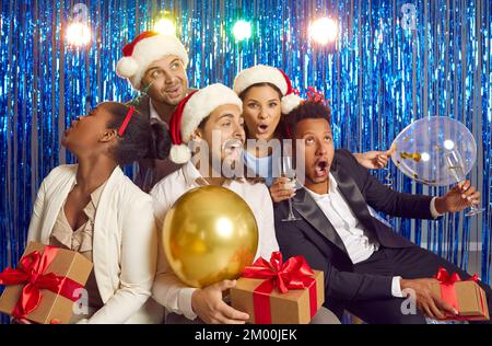 Cheerful funny young friends or colleagues having fun and fooling around at New Year's party. Stock Photo