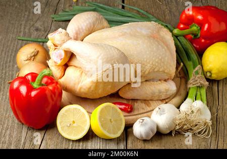 Whole uncooked Christmas turkey with vegetables on a wooden table Stock Photo