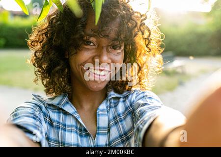 young biracial woman taking selfie on sunset outside, female person with genetic vitiligo smiling at the camera, happy people and body positive concep Stock Photo