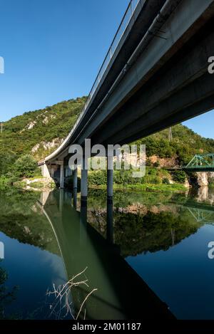 Two bridges over the river - one railway and one traffic bridge. Reflections in the water. Stock Photo