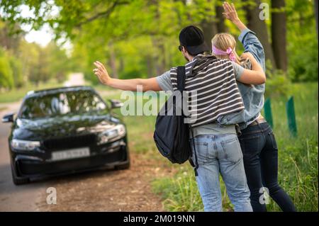 On the way to the city. Young people in the forest stopping the car and looking joyful.