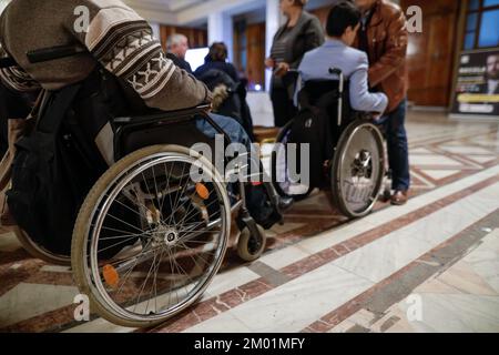 Shallow depth of field (selective focus) details with a man in a wheelchair during a convention. Stock Photo