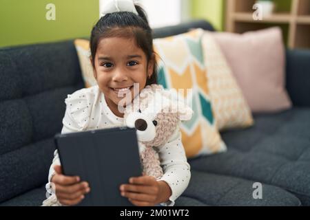 Adorable hispanic girl using touchpad sitting on sofa at home Stock ...