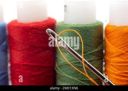 Multi-colored spools of thread close-up. Needle with thread. Seamstress or tailor's tools Stock Photo