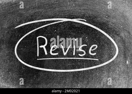 White chalk hand writing in word revise on blackboard background Stock Photo