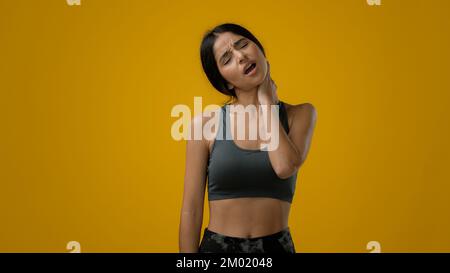 Sad sick ill unhappy Indian sporty woman sports lady athlete sport girl has neck pain problem with posture injury ache discomfort bad feeling muscle Stock Photo