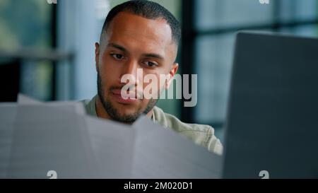 Serious pensive thinking African Latina businessman boss auditor checking corporate paperwork correspondence male entrepreneur reading documents think Stock Photo