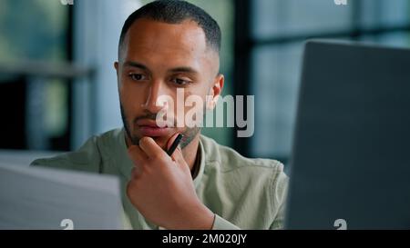Serious pensive thinking African ethnic businessman boss auditor checking corporate paperwork correspondence male entrepreneur reading documents think Stock Photo
