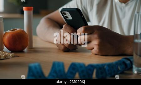 Close up male hands browsing mobile phone guy nutritionist unrecognizable man sport trainer counting calories with smartphone app healthy nutrition Stock Photo