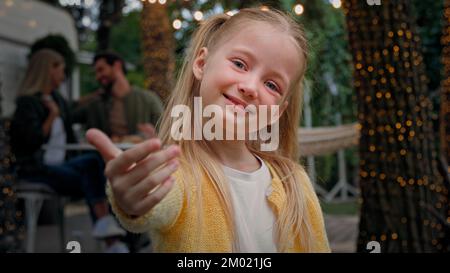 Portrait cute little child outdoors camping small kid girl baby schoolgirl daughter waving hand inviting welcome gesture come here invite Caucasian Stock Photo