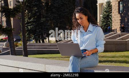 Business woman employer manager work online studying with computer sitting in city outdoors. Girl student typing laptop browsing web service sit on Stock Photo