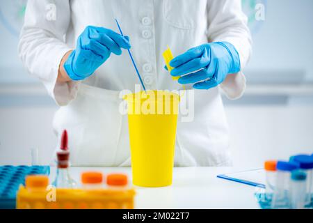 Throwing away medical waste in a hazardous waste container Stock Photo