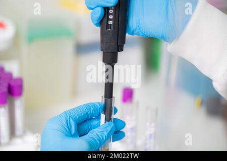 Researcher using a micropipette in a lab Stock Photo
