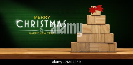 Wooden Christmas tree (made of small wooden cubes) with a red comet star on a wooden table with copy space and text Merry Christmas and Happy New Year Stock Photo