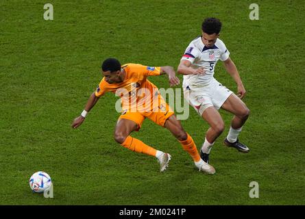 Netherlands' Cody Gakpo (left) and USA's Antonee Robinson battle for the ball during the FIFA World Cup round of 16 match at the Khalifa International Stadium in Al Rayyan, Qatar. Picture date: Saturday December 3, 2022. Stock Photo