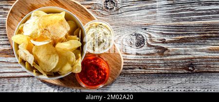 Composition with a bowl of potato chips and dipping sauces Stock Photo