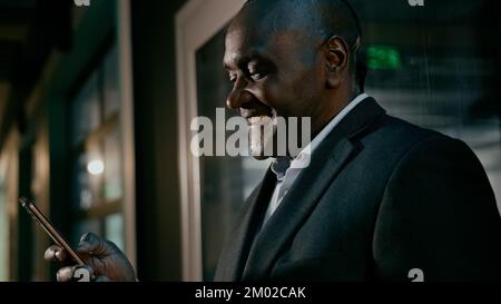 Happy smiling mature man holding phone browsing email writing text message uses mobile application satisfied businessman communicates with client on Stock Photo