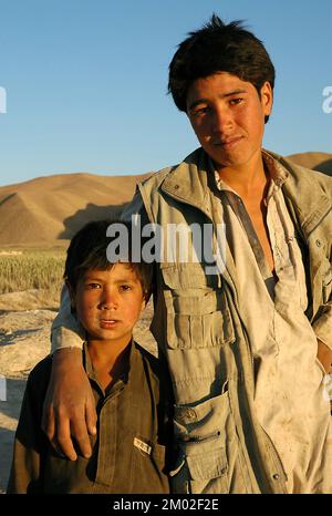 Dowlat Yar, Ghor Province / Afghanistan: Portrait of a young Afghan man with his arm around a young boy near Dowlatyar in central Afghanistan. Stock Photo