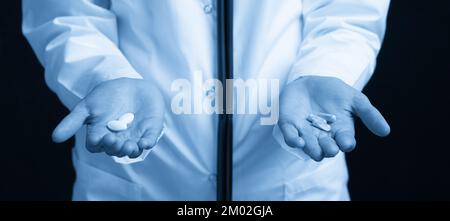 Cropped view of female Doctor holding in hands Pills to choose. Difficult Choice between drugs. Placebo drugs concept. Healthcare concept. Stock Photo