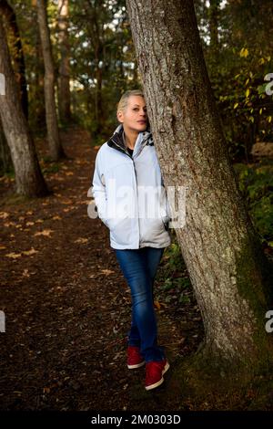 Attractive blonde woman walking in the forest on a nature hike Stock Photo