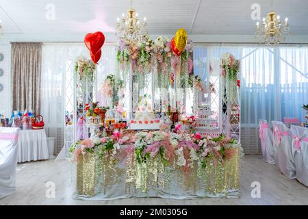 A big cake on the bride's table. The wedding table of the bride and groom is decorated with many different flowers Stock Photo