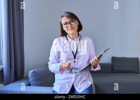 Portrait of female psychologist with clipboard sitting in office Stock Photo