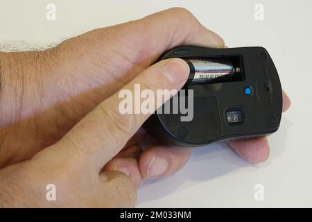 Closeup of man putting AA battery in wireless mouse Stock Photo