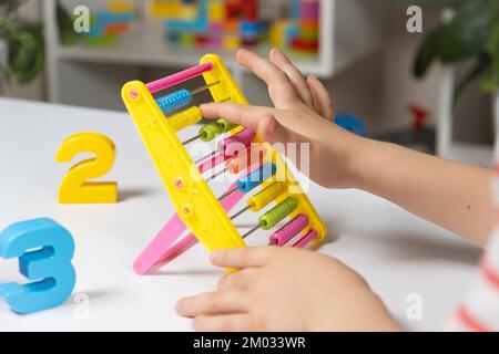 A small child learns to count on abacus, mathematics, arithmetic for children. Stock Photo