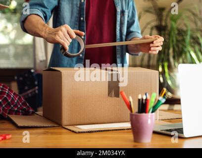 Man sealing parcel with duct tape Stock Photo