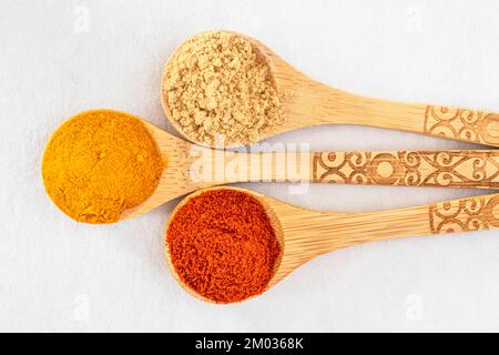 Close-up of coloured spices in wooden spoons on a white background Stock Photo