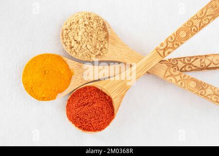 Close-up of coloured spices in wooden spoons on a white background Stock Photo