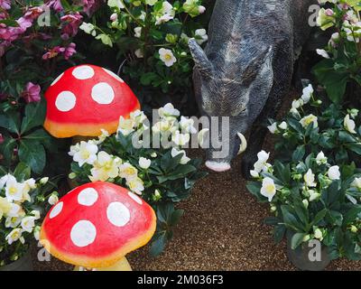 Sculpture of a wild boar in a garden with flowers Stock Photo