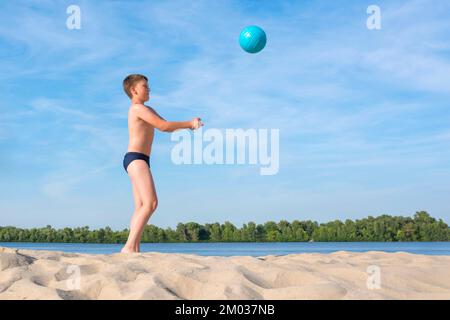 A boy plays beach volleyball. Side view. Sport lifestyle Stock Photo