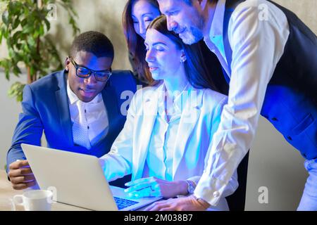 Multiethnic colleagues work together using pc. African mentor explains application aid to interns during group meeting. Coaching, teamwork concept. Stock Photo