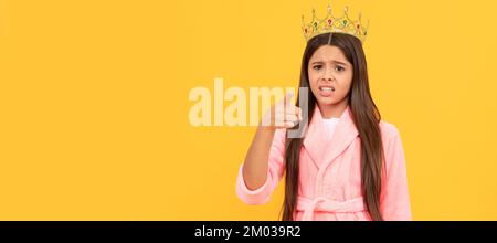 selfishness and egoism. oops. confused egocentric teen girl in crown pointing finger on camera. Child queen princess in crown horizontal poster design Stock Photo