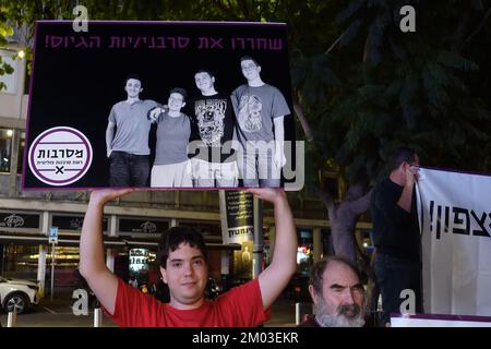 TEL AVIV, ISRAEL - DECEMBER 3: An Israeli teenager holds a sign which shows photo of young Israeli conscientious objectors, who are currently imprisoned in a military prison because they refuse to enlist in the army, during a rally calling for their release on December 3, 2022 in Tel Aviv, Israel. Military conscription is mandatory for young Israelis, and refusal or evasion to enlist without the army’s approval is a punishable offense. Conscientious objectors often spend months in military jail over several consecutive periods, until the army decides to discharge them. Credit: Eddie Gerald Stock Photo