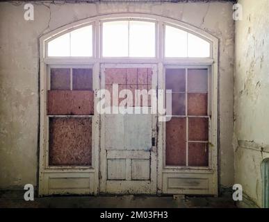 Abandoned old house entrance door with wood boards and hazy sunlight Stock Photo
