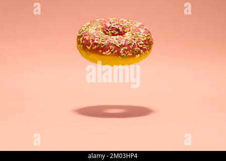 Levitating pink donut on pink background. Creative food background. Minimal wallpaper Stock Photo