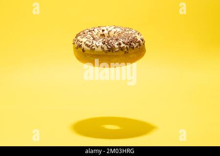 Levitating yellow donut on a yellow background. Creative sweet concept Stock Photo