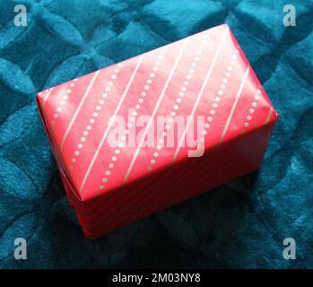 A Small Gift Box Wrapped in Red and Gold Paper Stock Photo