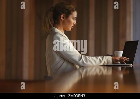 Female developer working on a laptop in a coworking space. Professional business woman working remotely. Woman doing freelance tech work. Stock Photo