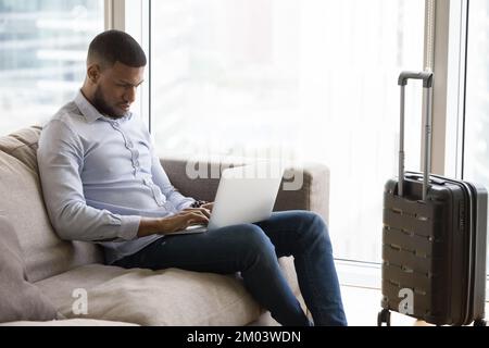 Serious young businessman using laptop on business trip for communication Stock Photo