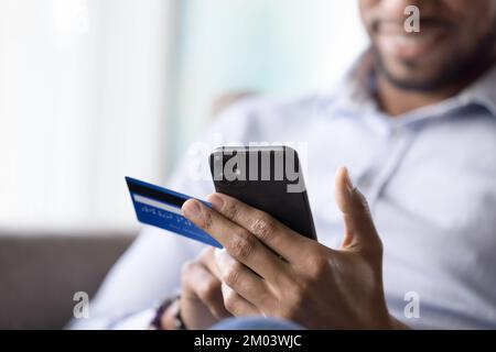 Focused mobile phone user man using credit card Stock Photo