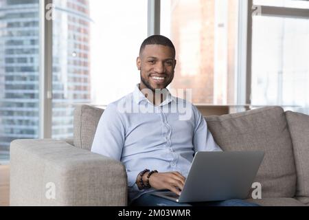 Happy confident handsome African business leader man sitting on couch Stock Photo