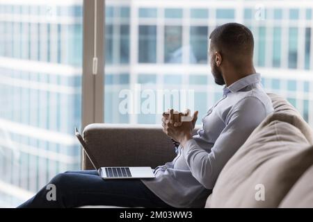 Thoughtful dreamy young African businessman thinking on project Stock Photo