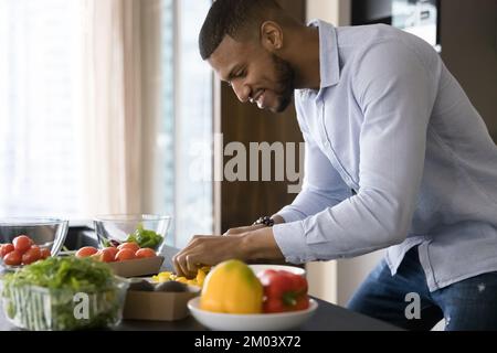Happy handsome young African chef guy cooking vegan meal Stock Photo
