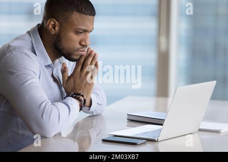 Focused pensive millennial Black businessman working at laptop in office Stock Photo