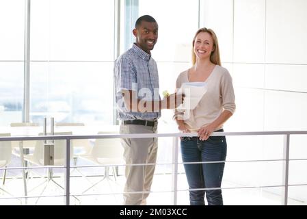 Together we achieve so much more. two business colleagues discussing paperwork in the office. Stock Photo
